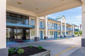 A multi-story hotel with a covered entrance, outdoor seating, and a parking lot.