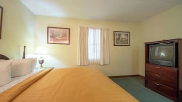 A hotel room with a bed, a television, a lamp, and two framed pictures on the wall.
