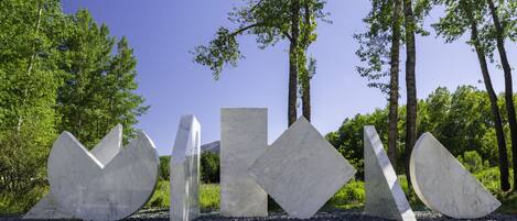 A sculpture garden with abstract marble sculptures in a natural setting.