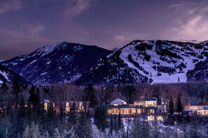 A modern multi-story building with large windows, surrounded by snow-covered mountains and trees. - Aspen Meadows Resort (Aspen)