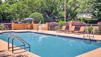 Una piscina al aire libre, sombrillas, sillones reclinables de piscina