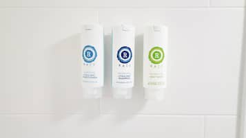Three toiletry bottles on a white tiled wall.