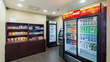 Un espace équipé de distributeurs automatiques proposant des en-cas et d’un réfrigérateur rempli de Coca-Cola.