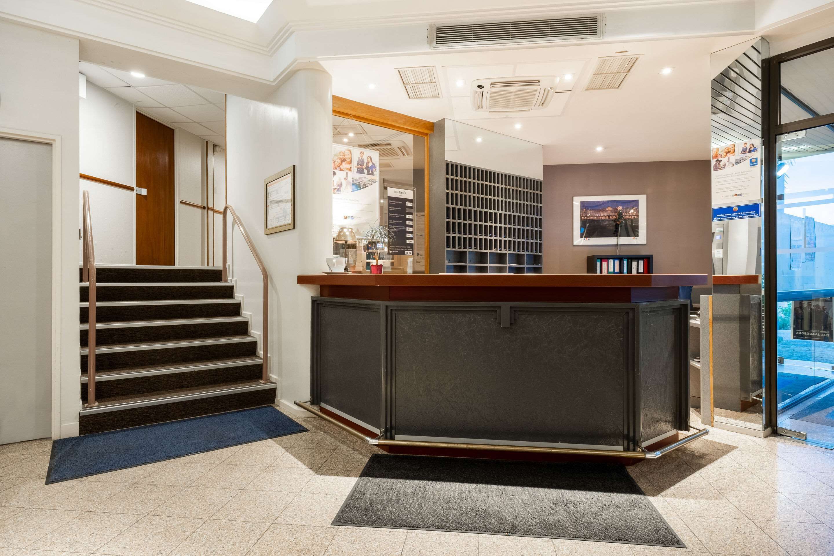 Un espace d’accueil comprenant un escalier, un comptoir de réception et une vue sur l’extérieur.