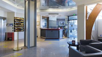 Eine moderne Lobby mit Empfangstresen, Sitzgelegenheiten und Pfeilen als Richtungsweiser auf dem Boden.