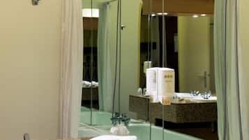 A bathroom with a large mirror, a sink, and a shower.