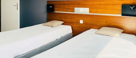A hotel room with two beds, a wooden headboard, a leopard print artwork, and a small table with a lamp.