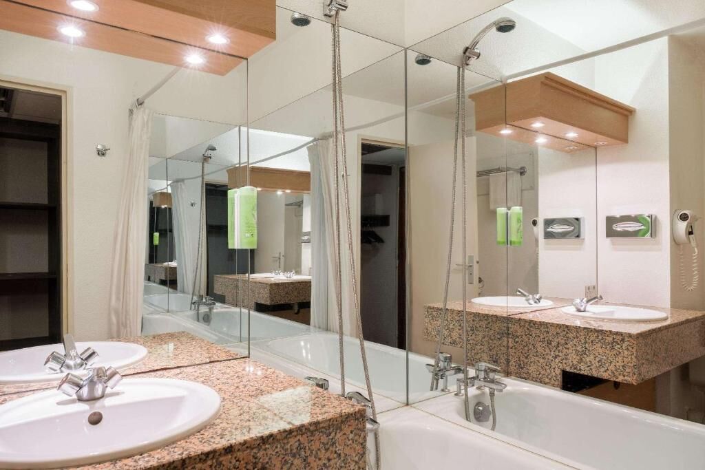 A modern bathroom with two sinks, a large mirror, and a shower.