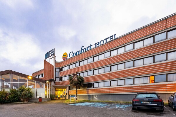 Un hôtel doté d’une façade moderne, de grandes fenêtres et d’une enseigne indiquant « Comfort Hotel ».