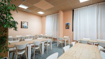Une salle de conférence dotée de plusieurs tables et de chaises, de grandes fenêtres avec des rideaux et d’œuvres d’art accrochées aux murs.