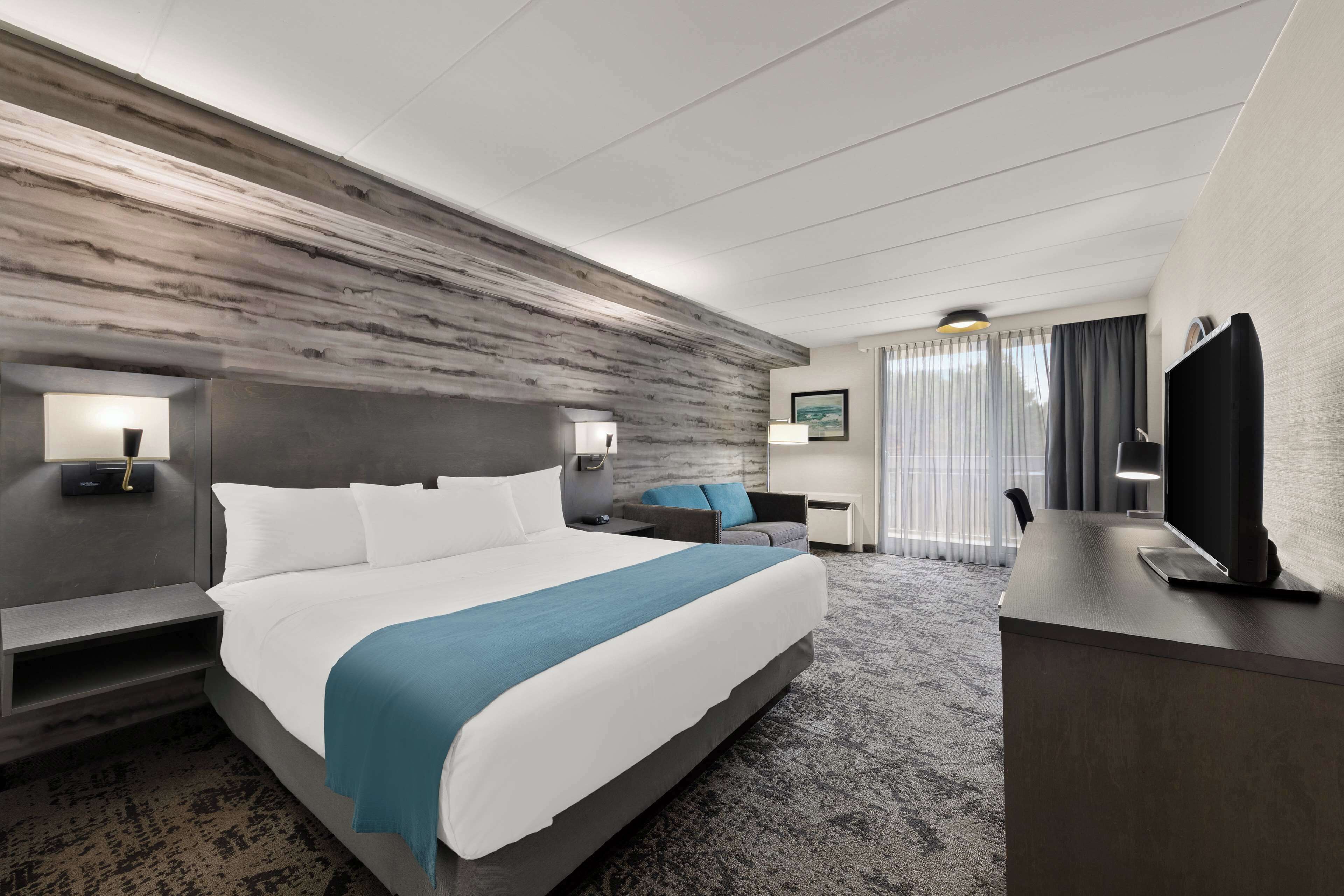 Une chambre d’hôtel moderne équipée d’un grand lit, d’un bureau, d’une chaise et d’un téléviseur.