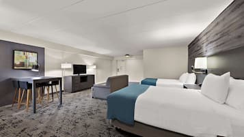 Ein Hotelzimmer mit zwei Betten, einem Schreibtisch mit Stuhl, einem Fernseher und einem Bild an der Wand.