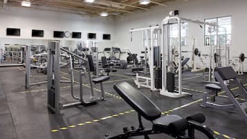 Un gimnasio con diversos equipos de ejercicio, incluyendo máquinas de pesas y bancos.