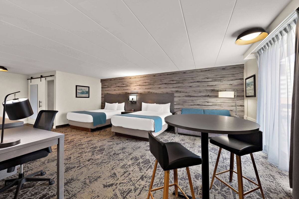 Habitació d'hotel amb un llit, una escriptori, una cadira, una taula rodona i un sofà.