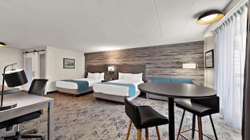Una habitación de hotel con cama, escritorio, silla, mesa redonda y sofá.