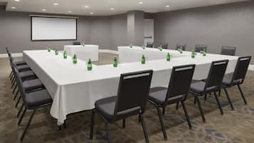 A conference room with a large table, chairs, and a projector screen.