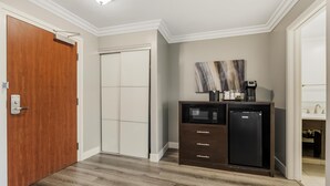 A compact kitchen with a microwave, refrigerator, and a coffee maker on a dark cabinet. - Best Western Plus LA Mid Town Hotel (Los Angeles)