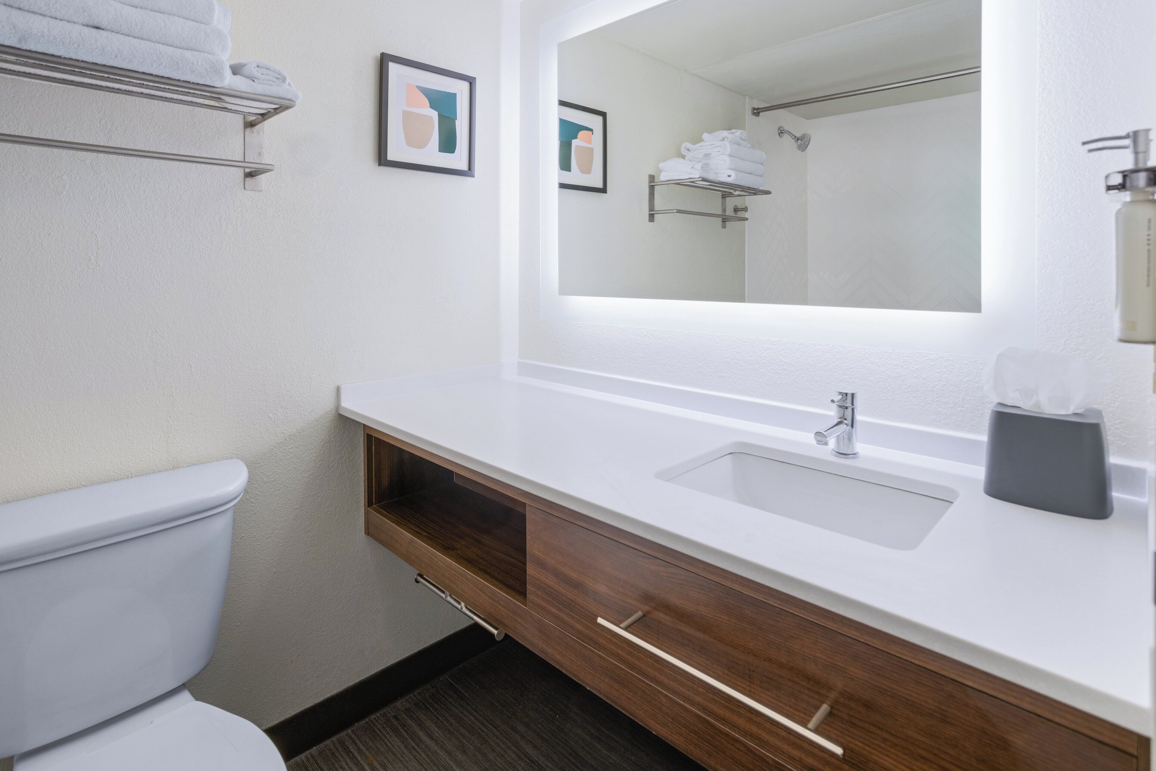 A modern bathroom with a white sink, wooden vanity, and a large mirror.