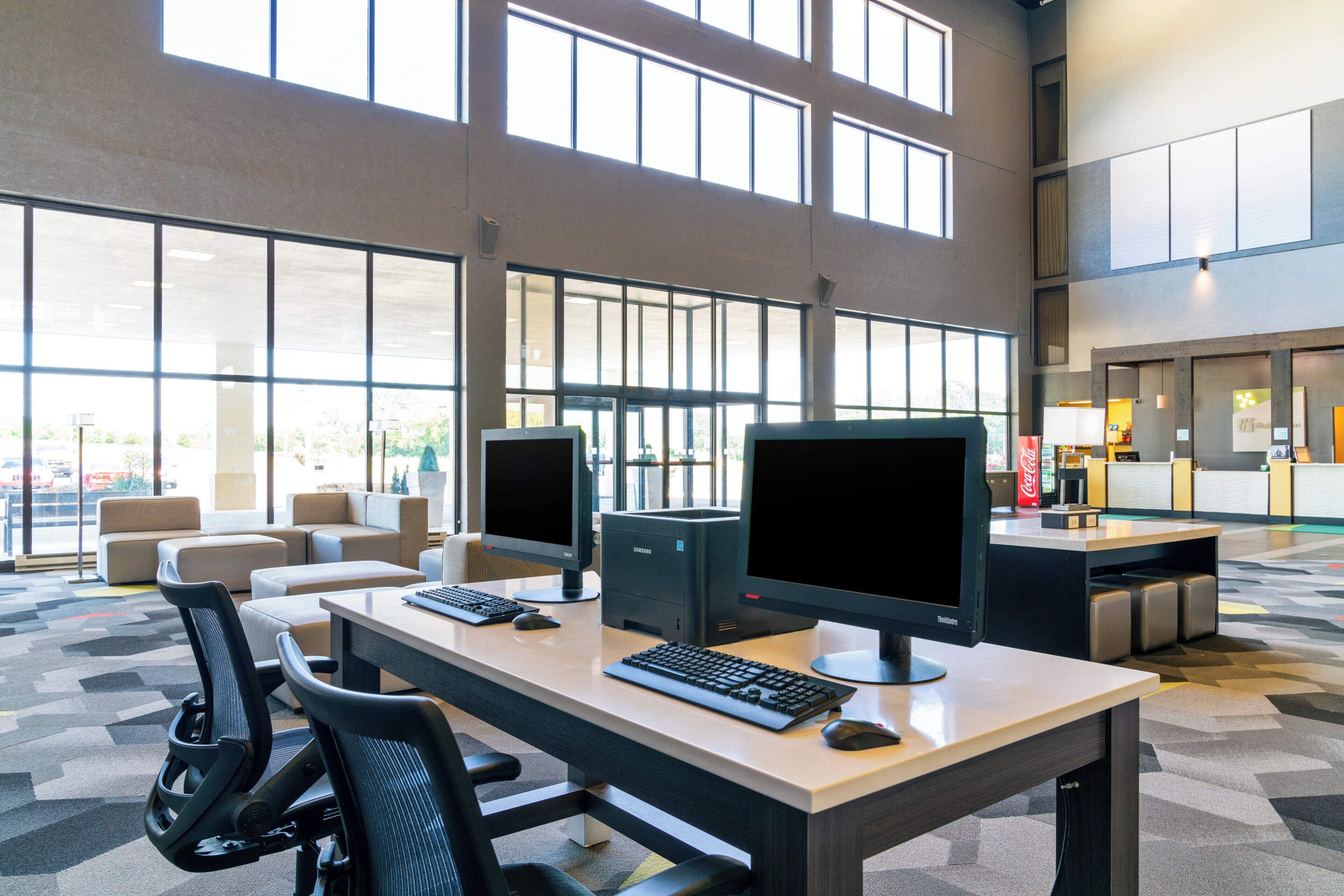A spacious, well-lit computer lab with multiple workstations, large windows, and a modern interior design.