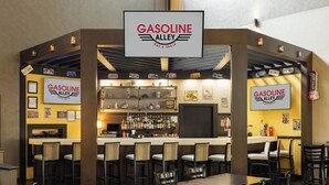 A bar area with a sign reading "Gasoline Alley Bar & Grille," featuring a bar counter, multiple seating options, and a variety of bottles on the shelves. - Holiday Inn Morgantown - Reading Area by IHG (Morgantown)