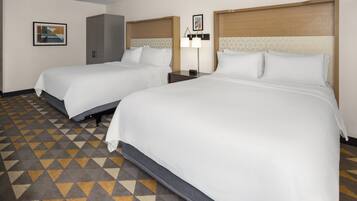 Una habitación de hotel con dos camas, un armario y una mesita de noche con lámpara.