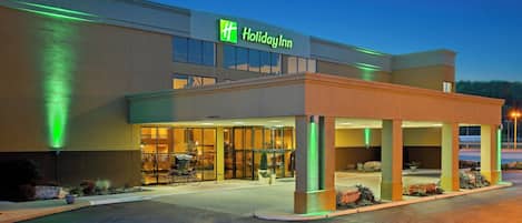 A Holiday Inn hotel with a modern design, featuring a covered entrance and a well-lit facade.