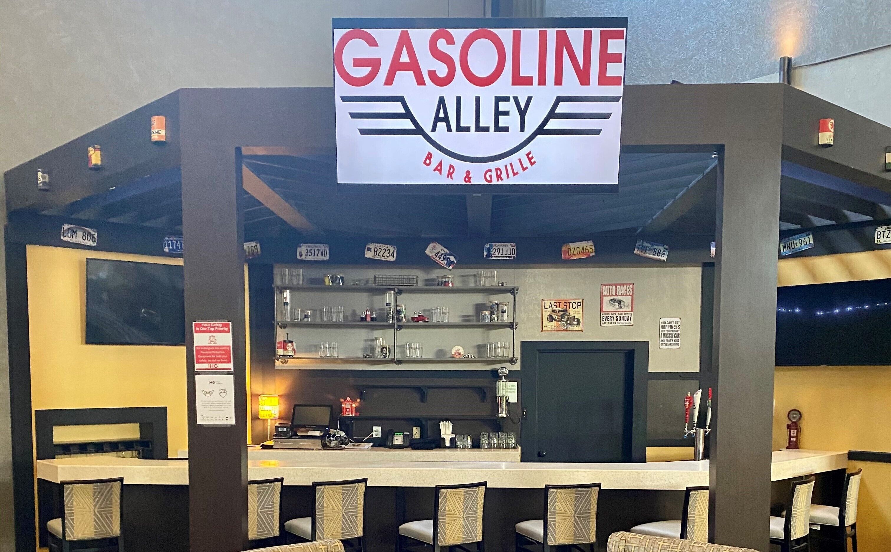 En bar og grill ved navn Gasoline Alley med en disk, siddeområde og forskellige skilte på væggene.