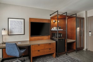 A hotel room with a desk, chair, TV, microwave, and wardrobe. - Four Points by Sheraton Los Angeles Westside (Culver City)