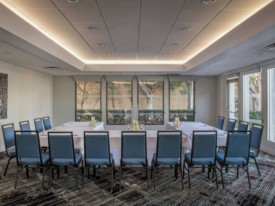 A conference room with a long table, blue chairs, and large windows.