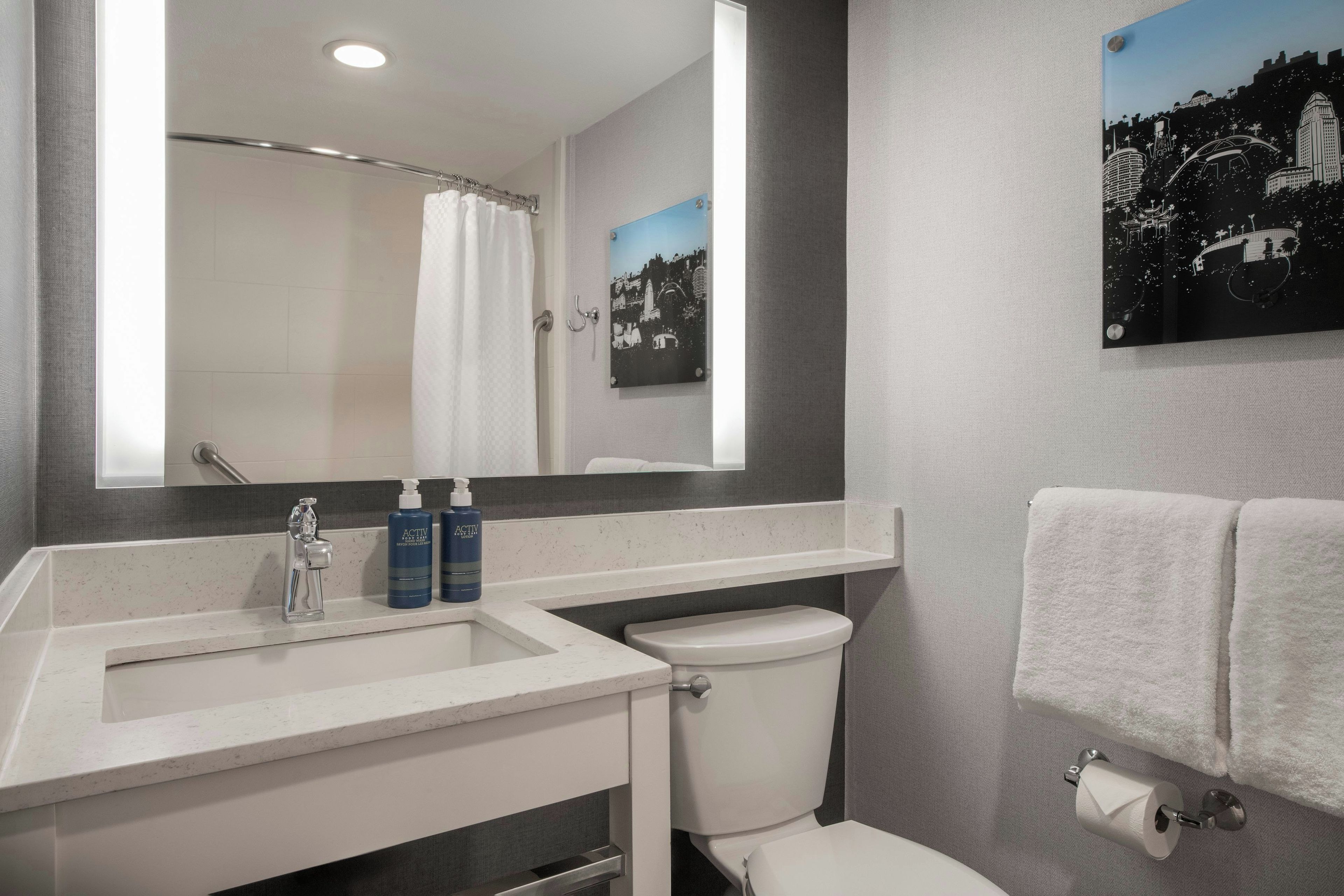 A bathroom with a white sink, a toilet, a mirror, and a towel rack.