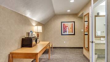 A hotel hallway with a wooden table, a microwave, a lamp, and a framed picture on the wall.