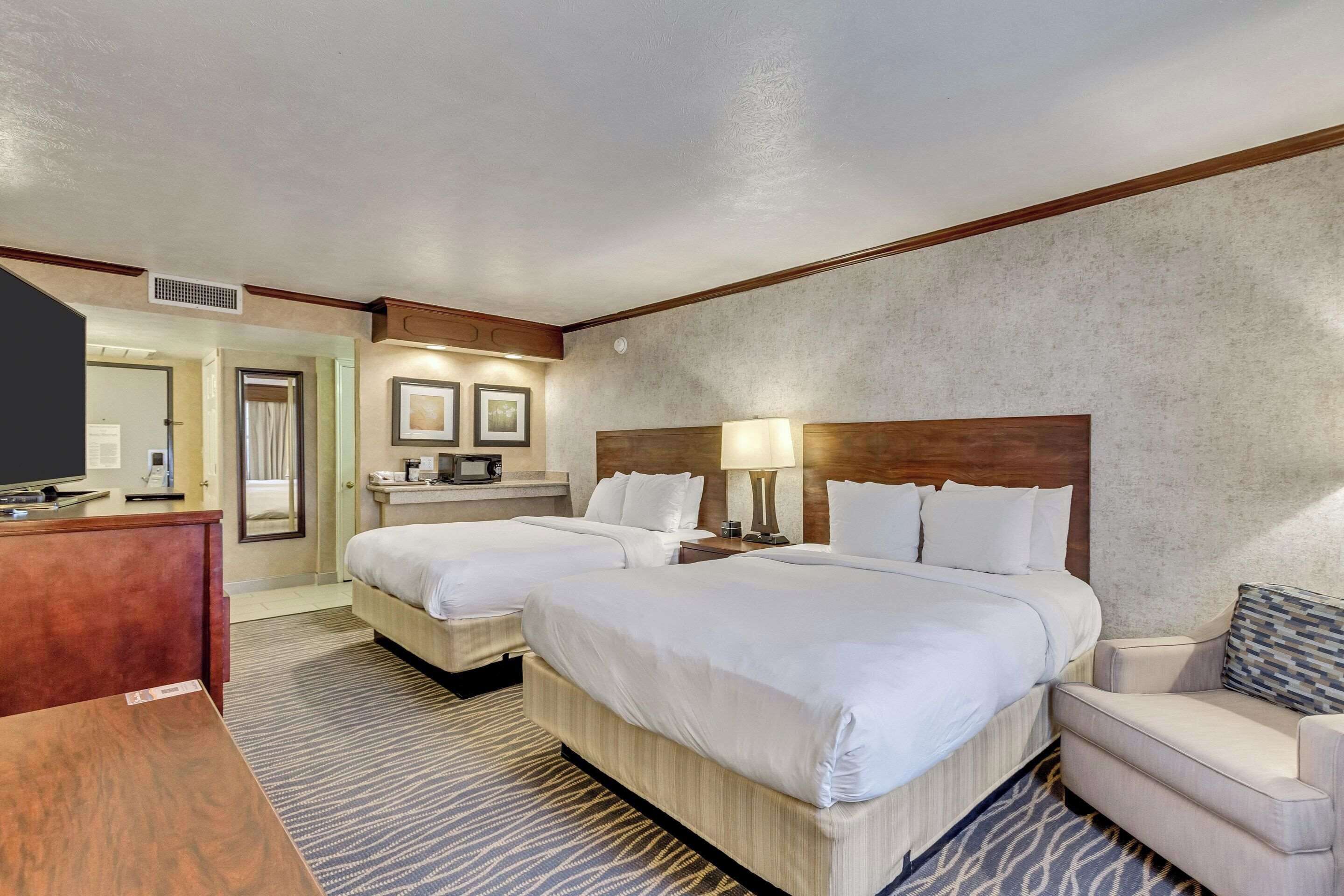 A hotel room with two beds, a desk, a TV, and a sofa.