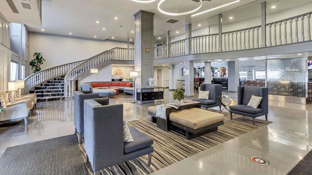 Eine großzügige Lobby mit Treppe, Sitzgelegenheiten und einem Restaurant.