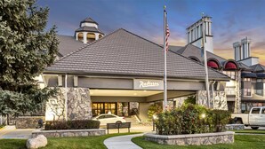 Ein Hotel mit einer Stein-Fassade, einer Fahnenstange mit der US-amerikanischen Flagge und einem geparkten Auto davor.
