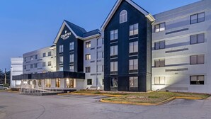 A modern hotel with a prominent 'Country Inn & Suites' sign, featuring a two-story structure with a flat roof and a large parking lot in front. - Country Inn & Suites by Radisson, Atlanta Airport South, GA (College Park)