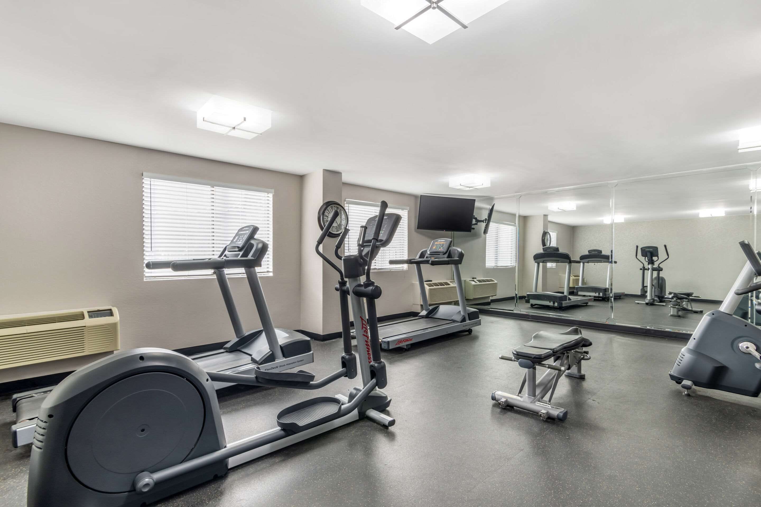 Une salle de sport équipée de divers appareils d’exercice, notamment des tapis de course, des vélos elliptiques et un vélo d’appartement.