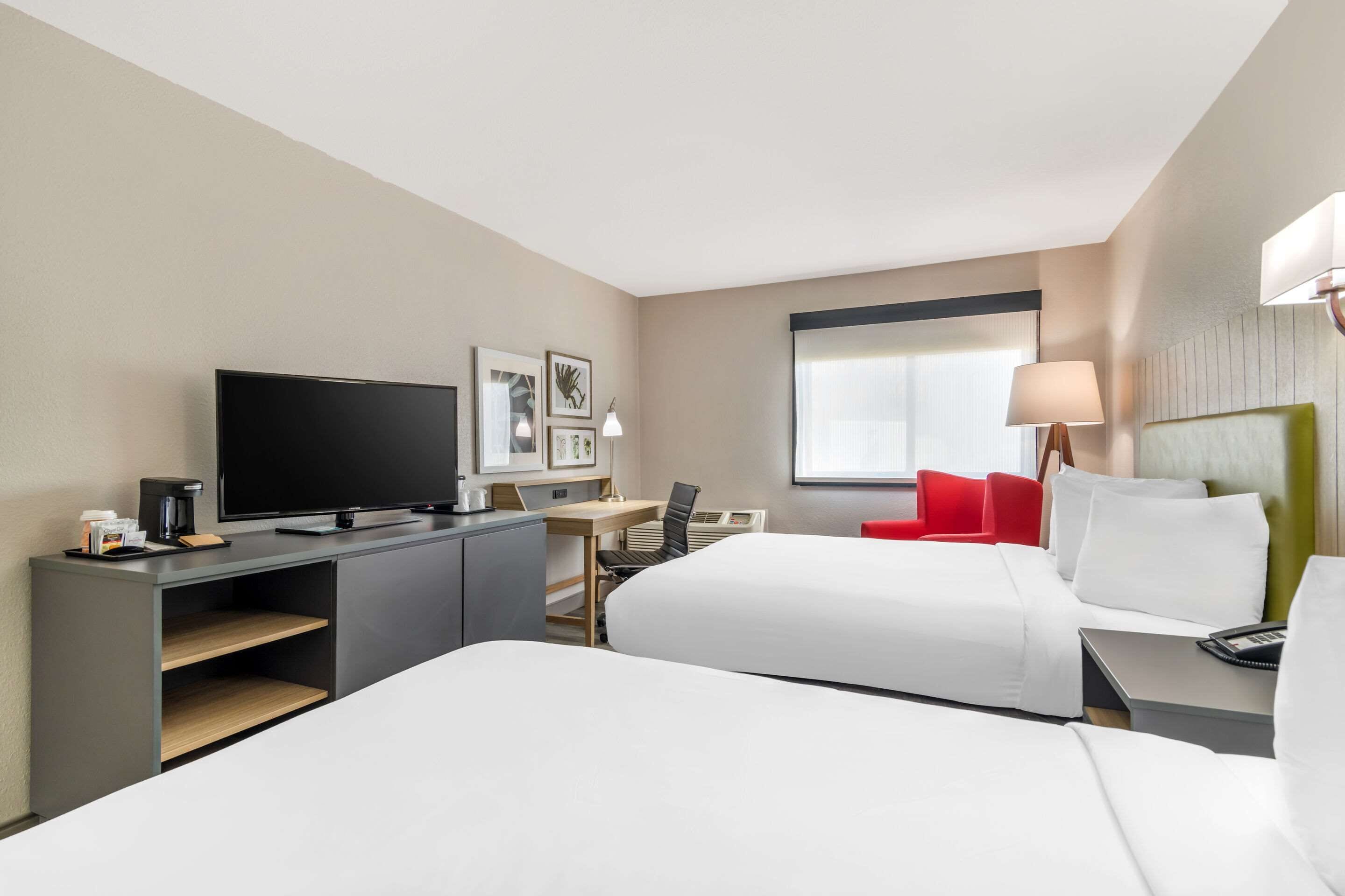 A hotel room with two beds, a desk with a computer, a television, and a coffee maker.