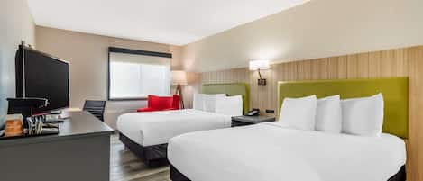 Una habitación de hotel con dos camas, un escritorio, un televisor y una ventana.