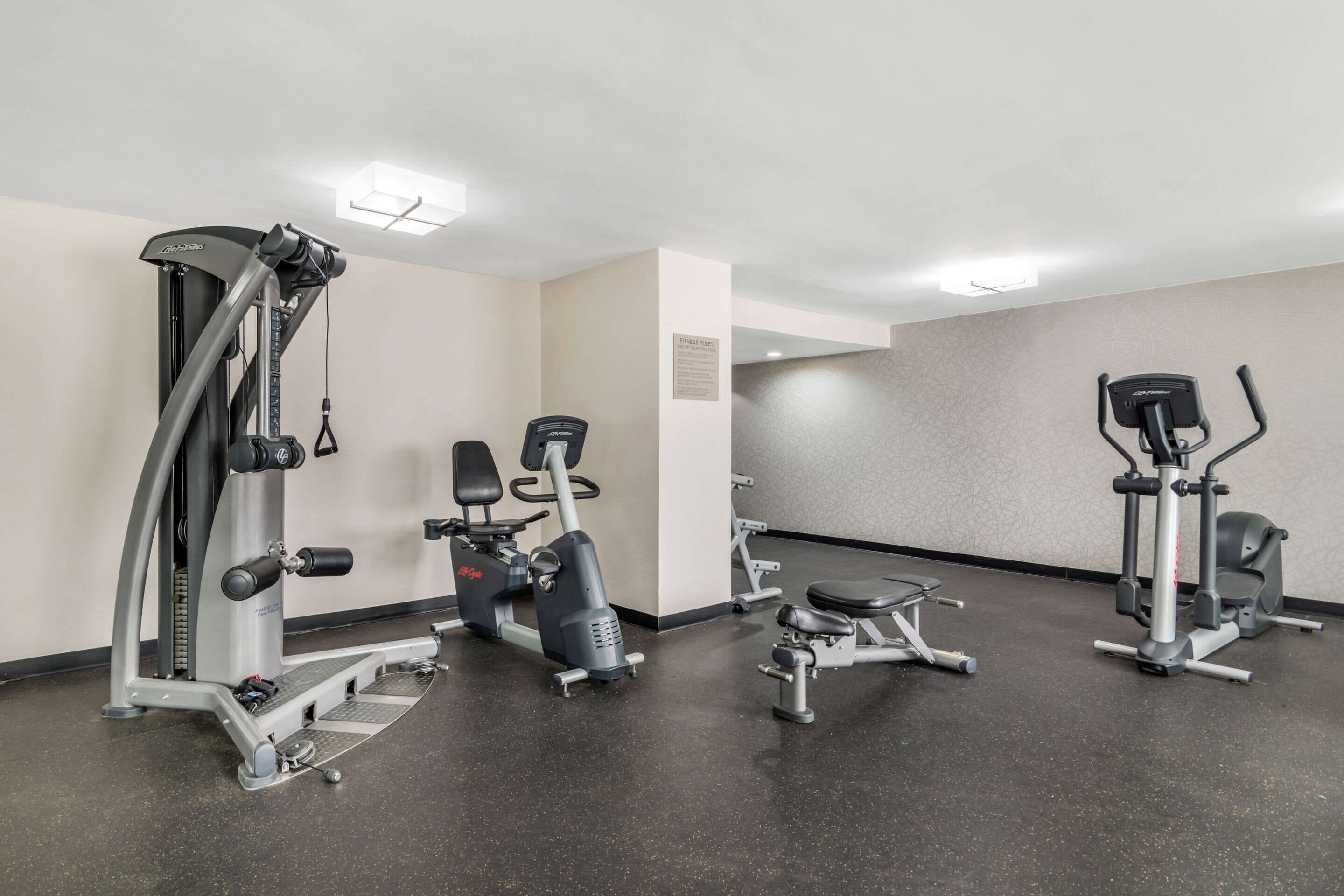 A gym with cardio machines, weight machines, and a bench.