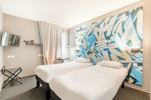 Een hotelkamer met twee bedden, een televisie, een klein tafeltje en een muur met abstracte kunst.