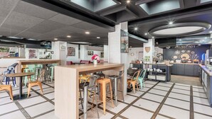 A modern cafe with a central bar area, seating arrangements, and a breakfast counter. - Ibis Styles Toulouse Centre Canal du Midi (Toulouse)
