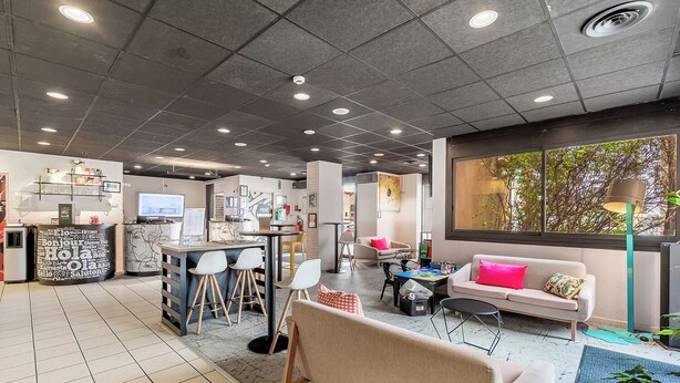 A modern interior with a bar area, seating, and a large window. - Ibis Styles Toulouse Centre Canal du Midi (Toulouse)