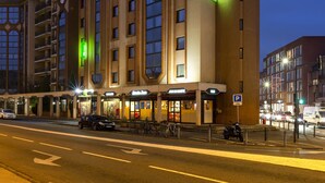 A multi-story hotel with a prominent "Ibis Styles" sign, a parking area, and a street with vehicles. - Ibis Styles Toulouse Centre Canal du Midi (Toulouse)