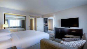 Una habitación de hotel con una cama grande, televisión, sofá y una pequeña kitchenette.