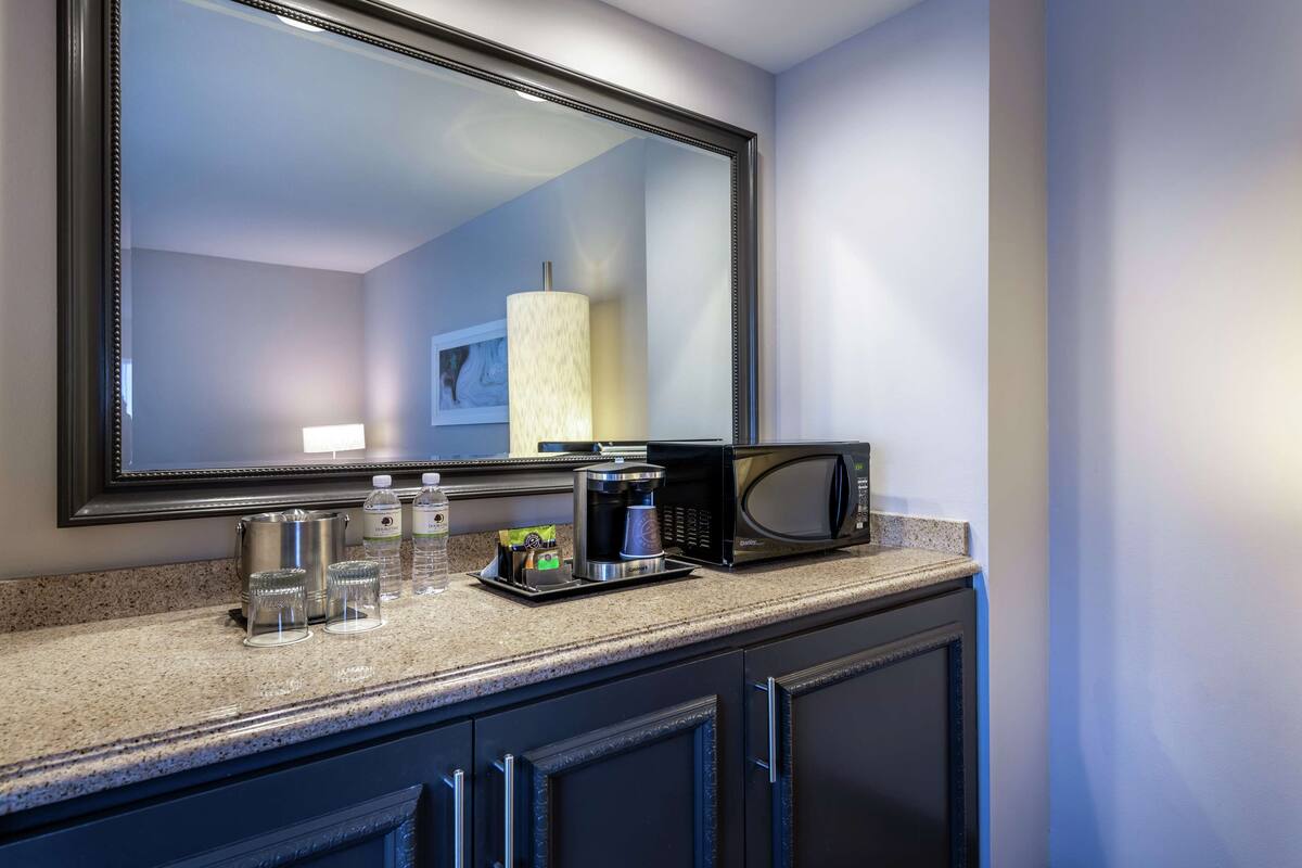 A kitchen with a microwave, coffee maker, and water bottles on the counter.