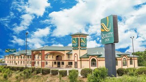 A hotel with a green roof, multiple indoor pool signs, and a clear blue sky. - Quality Inn Raton, NM (Raton)
