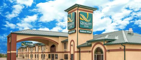 A Quality Inn with a prominent indoor pool sign, a covered entrance, and a series of rooms with a consistent architectural style.