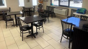 A restaurant interior with multiple tables and chairs, a clock on the wall, and large windows with a view of parked cars outside. - Quality Inn Raton, NM (Raton)