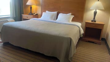 Une chambre d’hôtel avec un grand lit, deux tables de chevet avec des lampes, une tête de lit en bois et un sol recouvert de moquette.