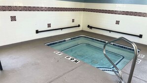 A swimming pool with a metal ladder, tiled walls, and a concrete floor with depth markers.